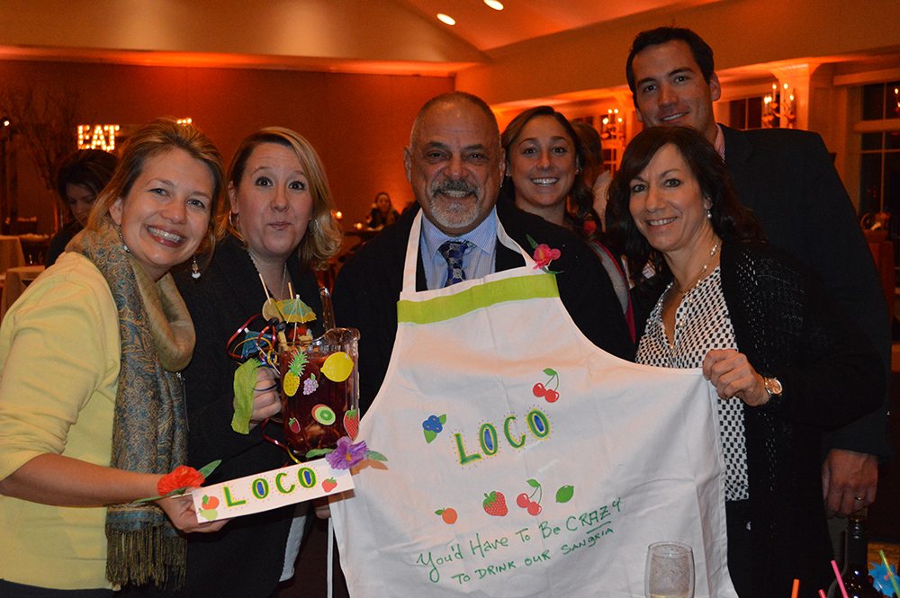 Employees posing for a photo with their Sangria drink and customize apron design.