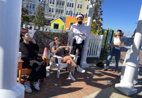 Participants engage in a scavenger hunt challenge during a Custom Team Building event. They are seated outdoors, fulfilling a task as part of the creative and interactive scavenger hunt activity.
