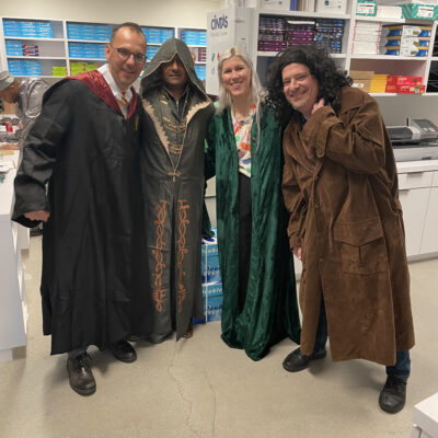 Four participants dressed in various fantasy costumes, including wizard robes and cloaks, pose together during a Custom Team Building event. Their creative outfits reflect the themed nature of the activity. thumbnail
