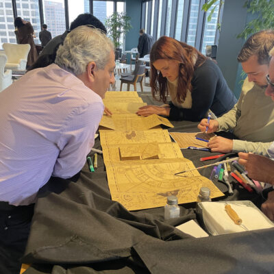 Participants work together on a detailed project involving intricate Harry Potter themed map during a Custom Team Building event. thumbnail