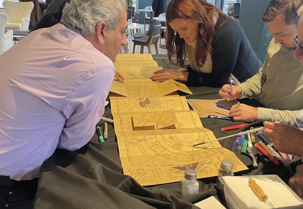 Participants work together on a detailed project involving intricate Harry Potter themed map during a Custom Team Building event.