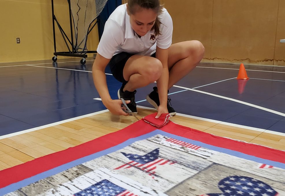 Team member diligently cuts fabric to assemble a fleece blanket during The Big Give charity team building event.