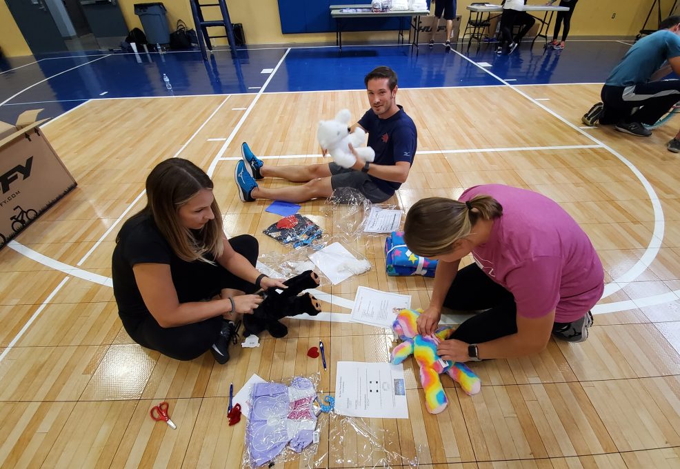 Team members assemble stuffed animals as part of The Big Give charity team building event, preparing toys for donation to children in need.
