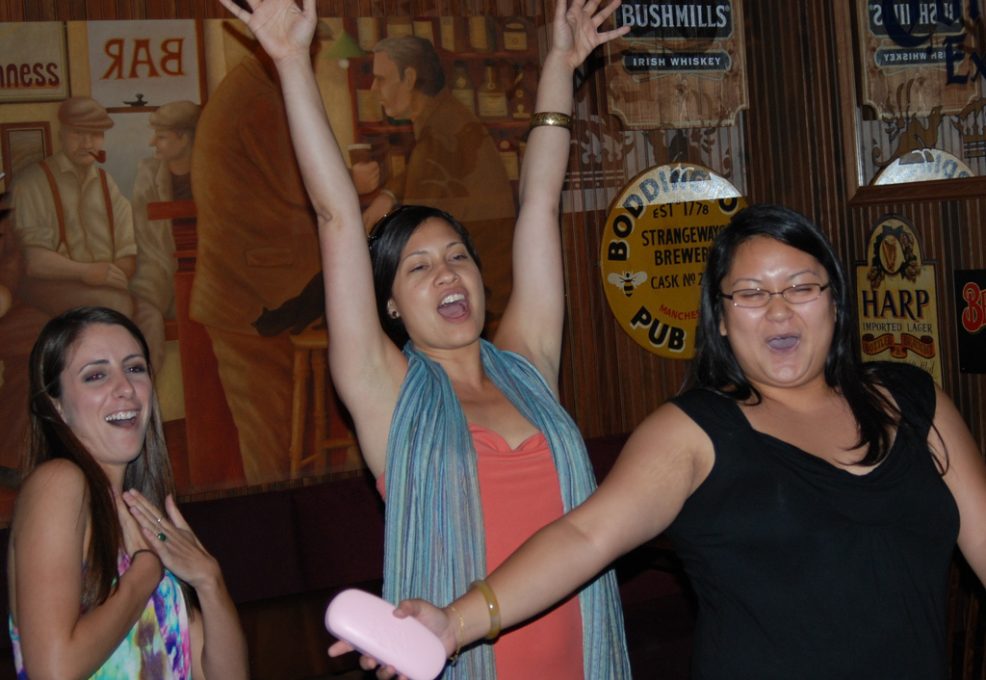 Three excited team members celebrate during a lively moment of the Pub Crawl Scavenger Hunt, capturing the thrill of teamwork and friendly competition.