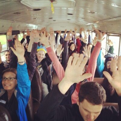 Group of people raising their hands with a smile in bus travel.