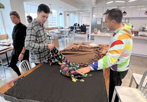 Participants at the Paws For A Cause team building event collaborate on creating large, comfortable dog beds for donation to local animal shelters, helping animals in need while fostering teamwork.