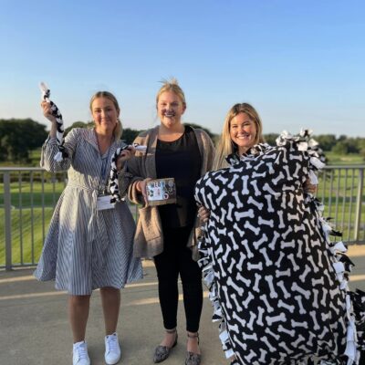 Team members proudly present their completed dog bed, toy, and treats after a successful Paws For A Cause team building event, benefiting local animal shelters. thumbnail