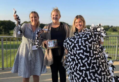 Team members proudly present their completed dog bed, toy, and treats after a successful Paws For A Cause team building event, benefiting local animal shelters.