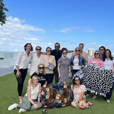 Team members at the Paws For A Cause team building event proudly showcase the colorful dog beds and pull toys they created for donation to a local animal shelter, smiling with a sense of accomplishment. thumbnail