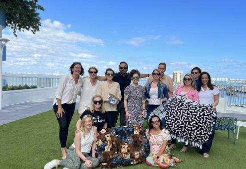 Team members at the Paws For A Cause team building event proudly showcase the colorful dog beds and pull toys they created for donation to a local animal shelter, smiling with a sense of accomplishment.