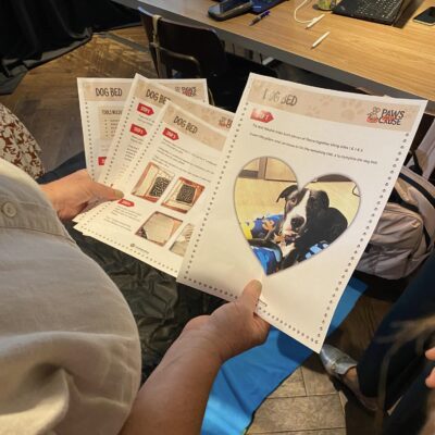 A participant at the Paws For A Cause team building event reviews step-by-step instructions for creating dog beds to be donated to local animal shelters, ensuring the project meets all requirements. thumbnail