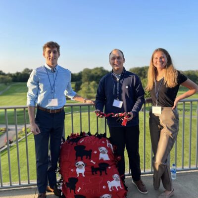 Three participants pose with their completed dog bed and toys during the Paws For A Cause team building event, helping to support local animal shelters. thumbnail