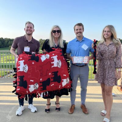 Participants proudly display their handmade dog bed and toys created during the Paws For A Cause team building event, supporting local animal shelters. thumbnail