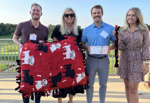 Participants proudly display their handmade dog bed and toys created during the Paws For A Cause team building event, supporting local animal shelters.