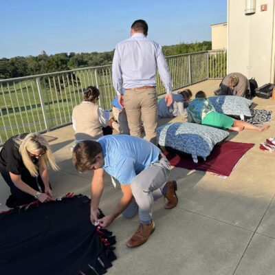 Team members work together outside, crafting dog beds during the Paws For A Cause team building event, supporting animal shelters in need. thumbnail
