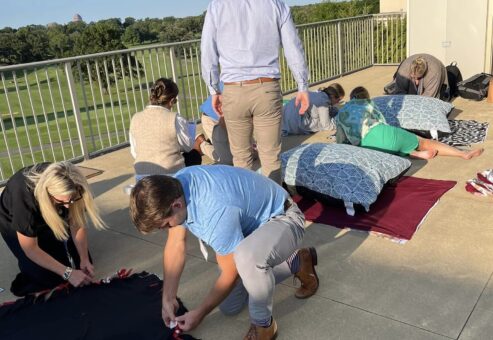 Team members work together outside, crafting dog beds during the Paws For A Cause team building event, supporting animal shelters in need.