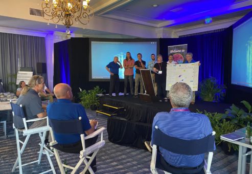 Team presenting a creative project on stage during a collaborative team building workshop.