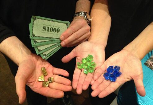 Four people, hands showing play cash, gold, green and blue rocks.