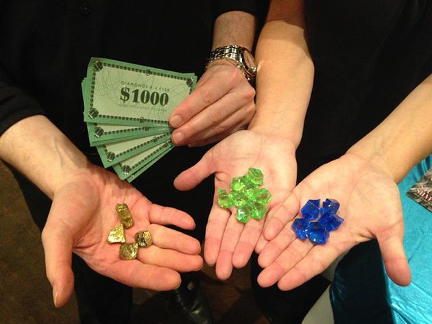 Four people, hands showing play cash, gold, green and blue rocks.