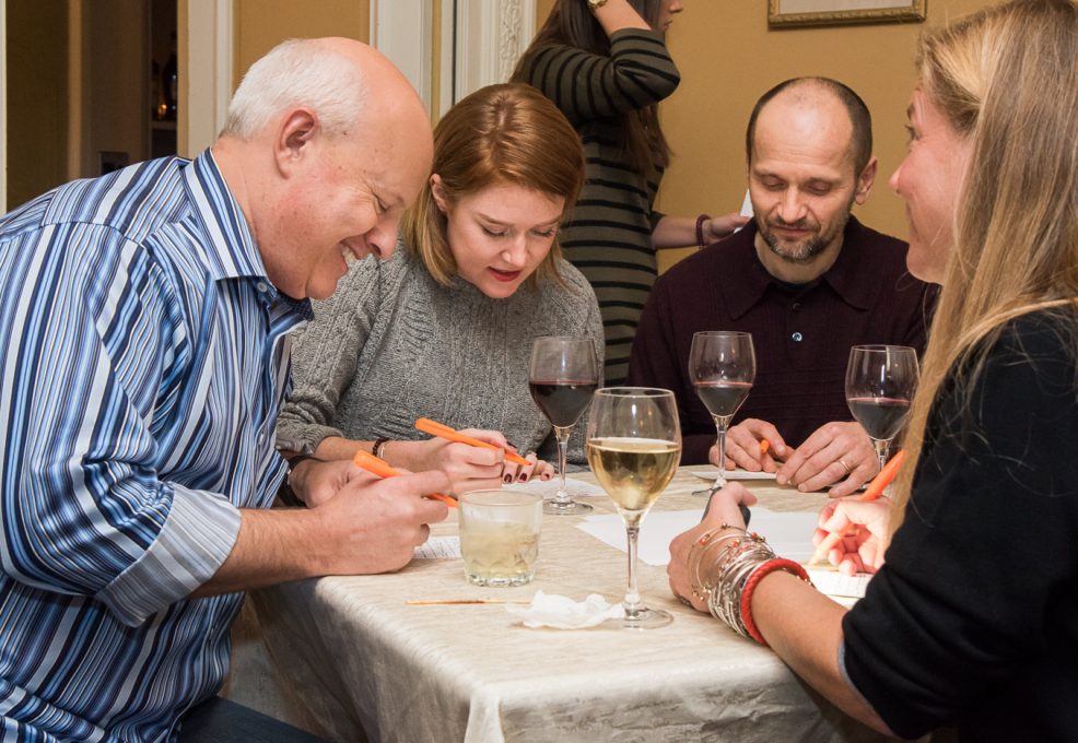 A small group of participants laughs and collaborates during the Wild Card Team Building Bingo event, with trivia and drinks adding to the fun atmosphere.
