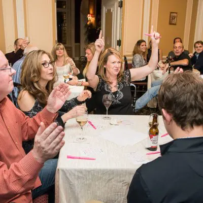 Enthusiastic participants raising their hands during a Wild Card Team Building Bingo game, showcasing engagement. thumbnail