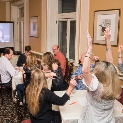 Excited participants raising their hands during a lively Wild Card Team Building Bingo event thumbnail