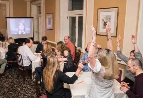 Excited participants raising their hands during a lively Wild Card Team Building Bingo event