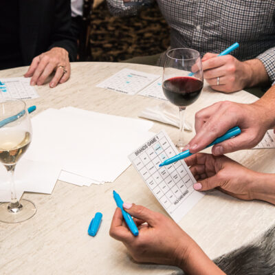 Close-up of players marking their bingo cards with colorful markers during a Wild Card Team Building Bingo event. thumbnail