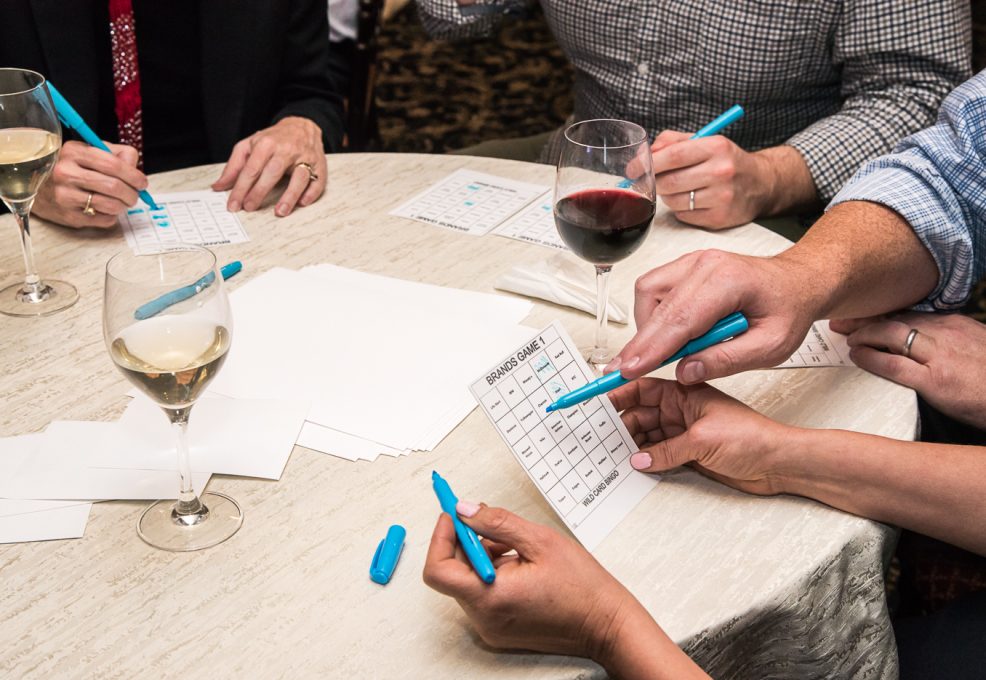 Close-up of players marking their bingo cards with colorful markers during a Wild Card Team Building Bingo event.