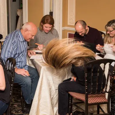 Engaged participants marking their bingo cards during the Wild Card Team Building Bingo event. thumbnail