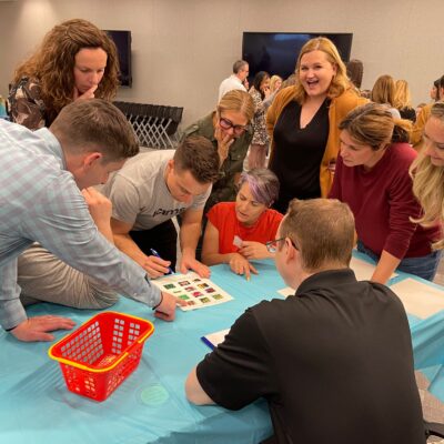 Team collaborates on a Foodbank Showdown challenge, using teamwork and strategy to complete a grocery-themed activity while preparing care packages for donation to local families in need. thumbnail