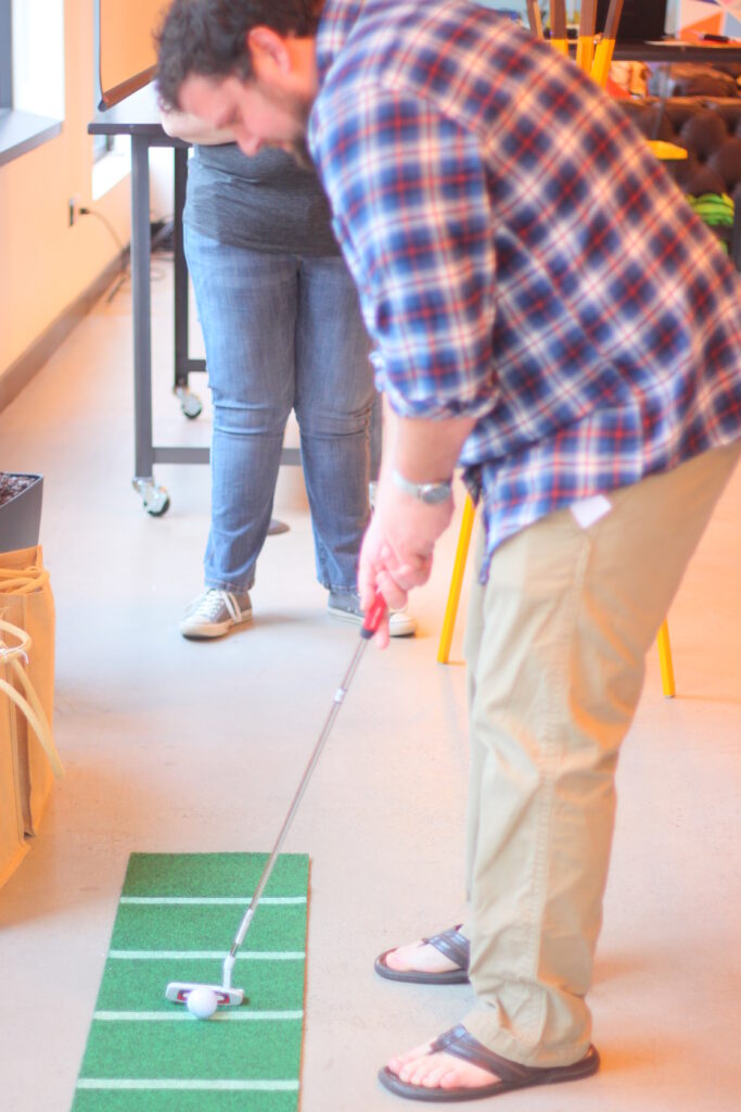 An employee is playing golf in the indoor area.