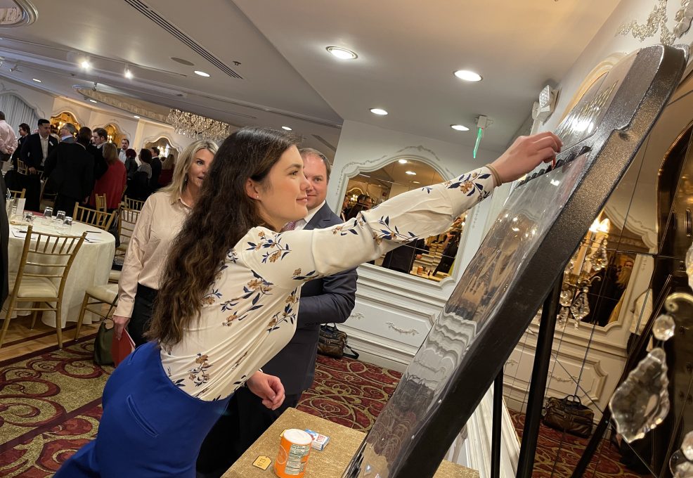 A participant enthusiastically places a marker on a large game board during the Foodbank Showdown team building event. The activity combines friendly competition with a charitable purpose, helping local families in need.