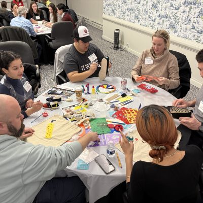 Teams creatively decorate TOMS shoes and tote bags during the Paint Soles for Souls team building event, using various paints and markers to design their unique artworks. thumbnail