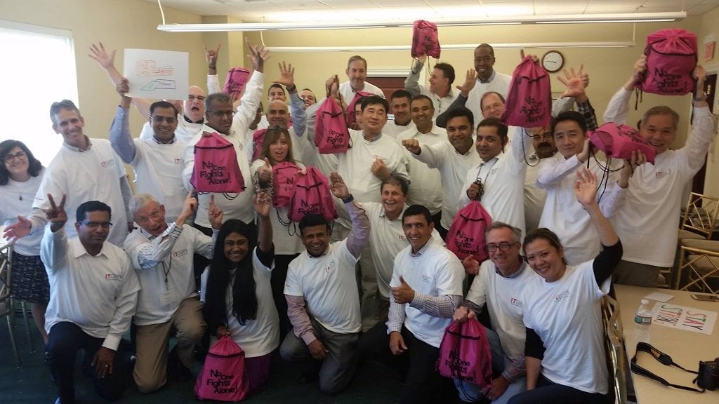 Employees raising their hands by sitting and standing with a smile.