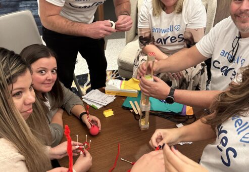 Team of participants working together on a crafting activity during a CSR event. They are creating handmade items as part of a team building project aimed at supporting a cancer patients.