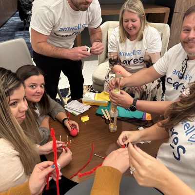 Team of participants working together on a crafting activity during a CSR event. They are creating handmade items as part of a team building project aimed at supporting a cancer patients. thumbnail