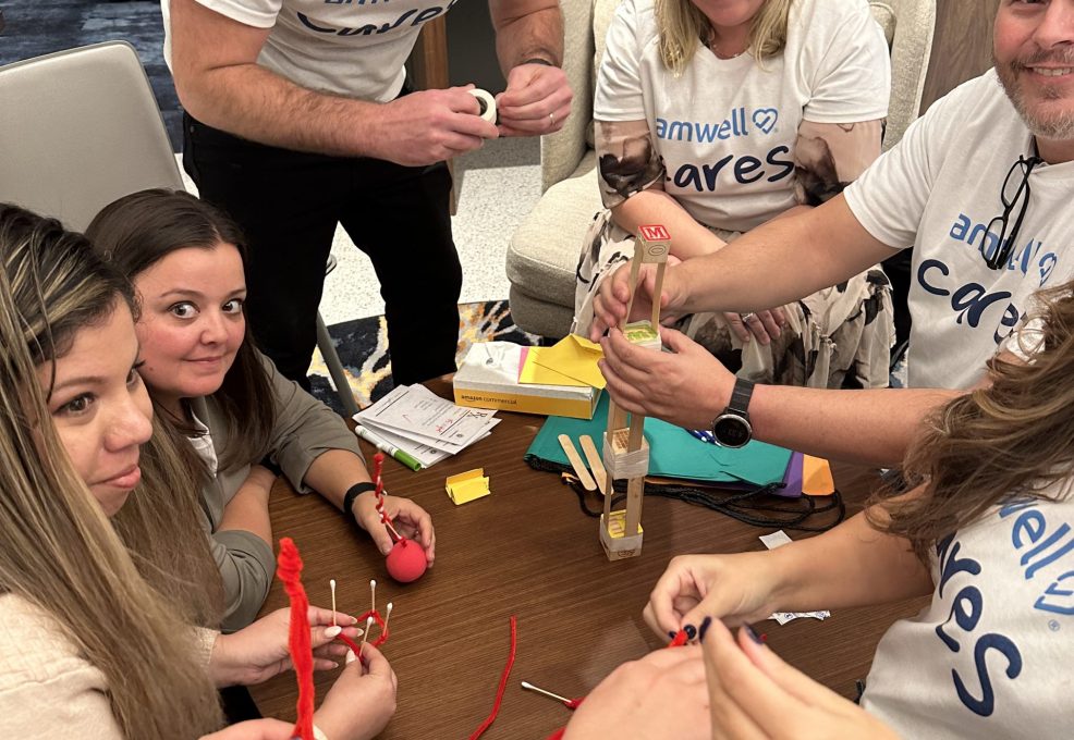 Team of participants working together on a crafting activity during a CSR event. They are creating handmade items as part of a team building project aimed at supporting a cancer patients.