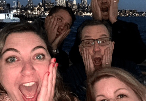 Team members mimic the iconic 'Home Alone' face while enjoying a fun and memorable moment during the Pub Crawl Scavenger Hunt with a stunning cityscape in the background.