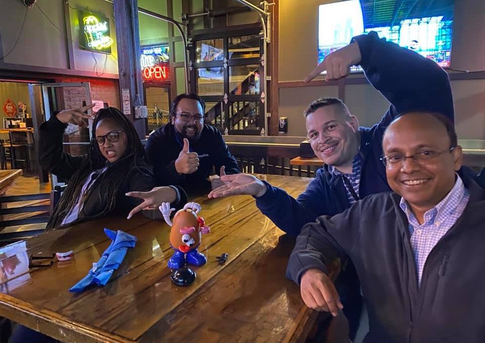 Team posing with Mr. Potato Head during a lively Pub Crawl Scavenger Hunt, fostering camaraderie and shared adventures in a relaxed pub setting.