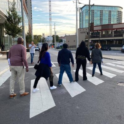 A team of colleagues crossing the street during their Pub Crawl Scavenger Hunt, exploring the city and taking part in fun challenges that encourage collaboration and friendly competition. thumbnail