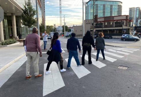A team of colleagues crossing the street during their Pub Crawl Scavenger Hunt, exploring the city and taking part in fun challenges that encourage collaboration and friendly competition.