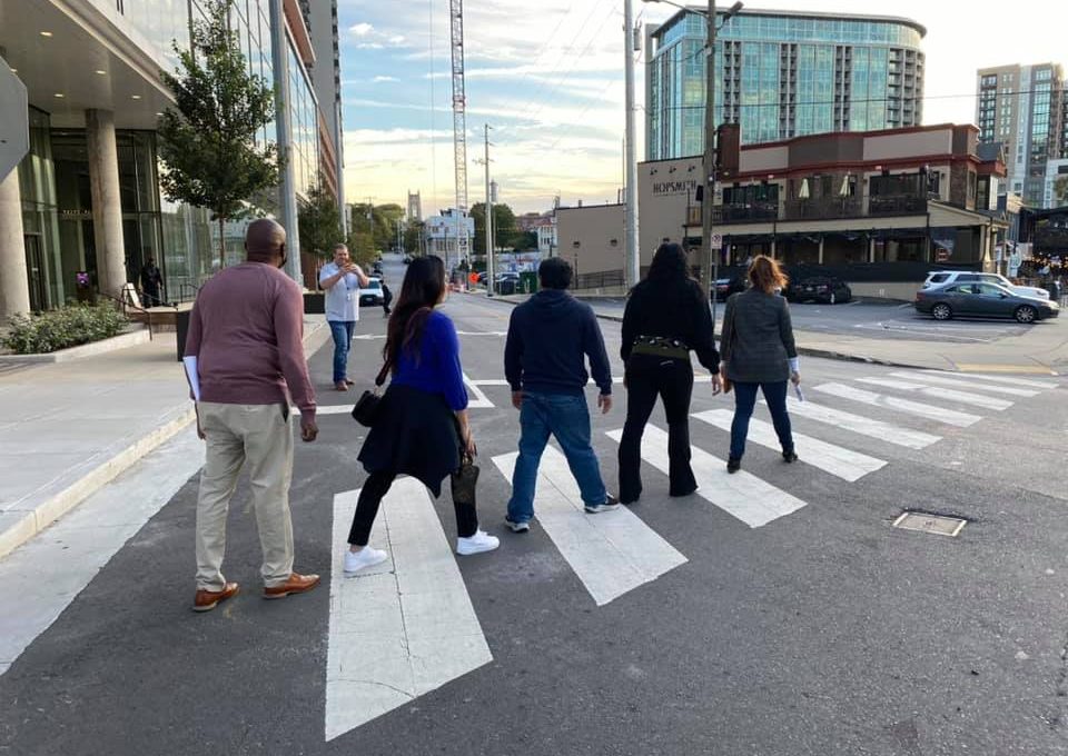 A team of colleagues crossing the street during their Pub Crawl Scavenger Hunt, exploring the city and taking part in fun challenges that encourage collaboration and friendly competition.