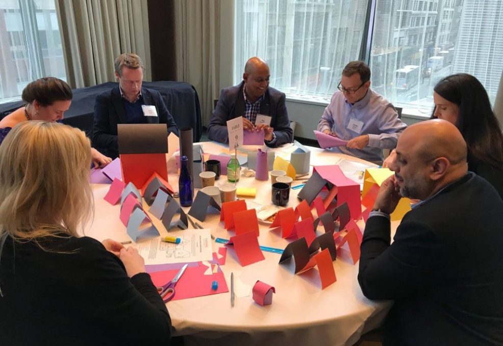 Participants sit around a table working together on assembling personal care kits during the Helping Hands team building event.