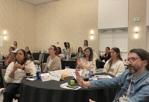 Participants attentively listen and engage during a board-breaking team building event, preparing to overcome personal and professional barriers.