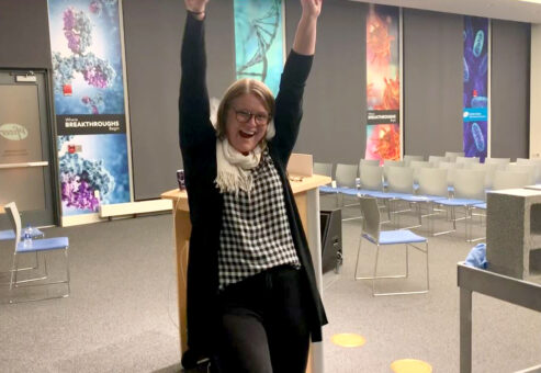 A participant celebrates with raised arms after successfully breaking a board during a team building activity focused on overcoming obstacles.