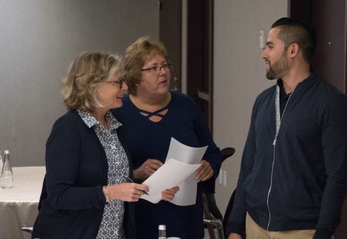 Three participants engaged in a conversation during the Team and Leadership DNA workshop, exchanging ideas and insights as they work through the activities.