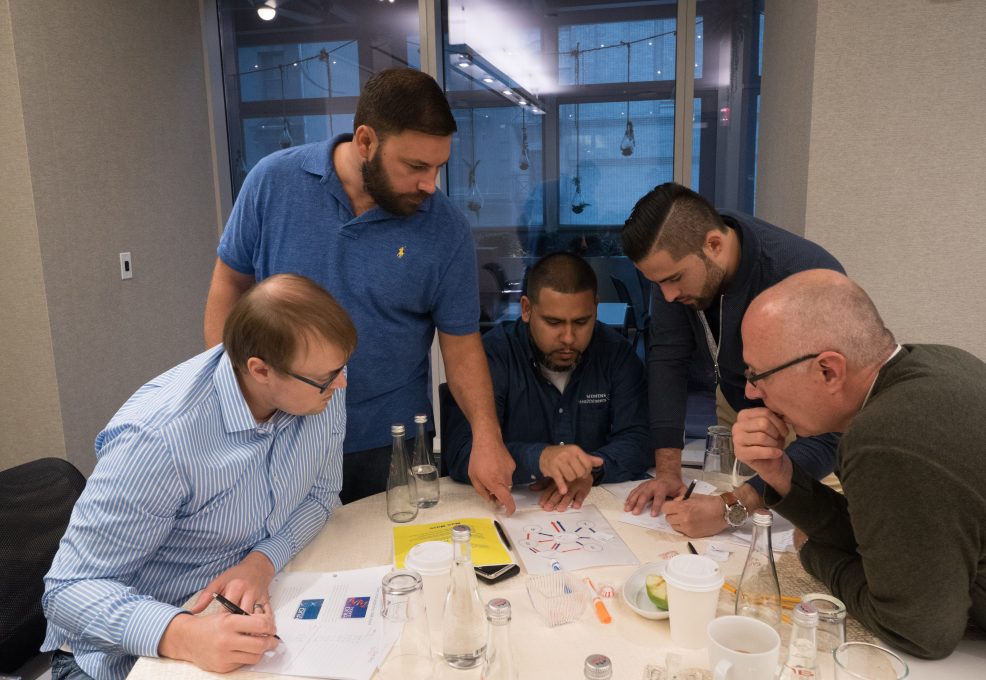 A group of participants collaborating during the Team and Leadership DNA session, analyzing data and discussing insights to improve team dynamics and leadership effectiveness.