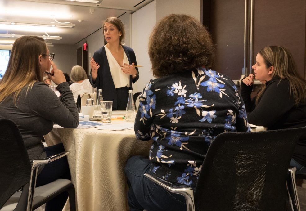 A facilitator leading a discussion with a small group of participants during the Team and Leadership DNA workshop, encouraging collaboration and sharing insights.
