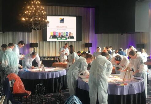 Participants in protective suits collaborate on an activity during the Team and Leadership DNA workshop, working at various stations to build insights and foster team development.